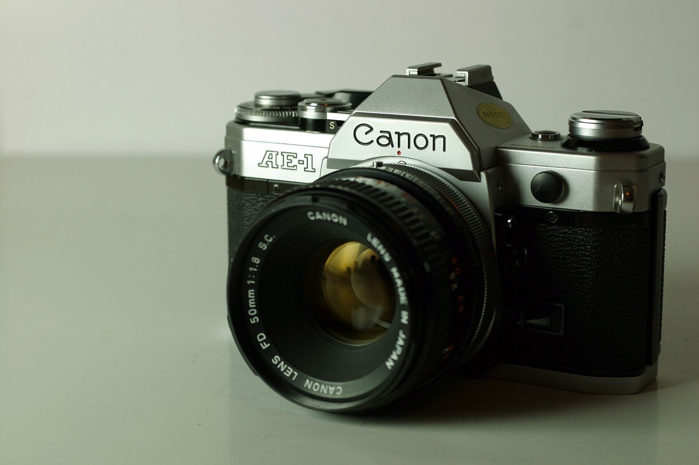 A silver Canon AE-1 film camera with a 50mm lens, seen from the front left